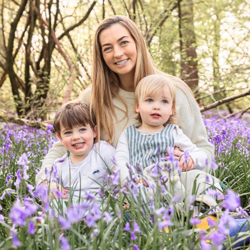 A mum sat amongst the bluebells with her children